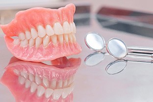 Full dentures and dental mirrors on reflective surface