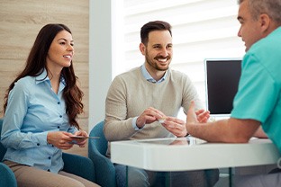 Dentist and couple talking in dental office