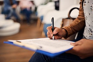 Woman filling out dental insurance form in lobby