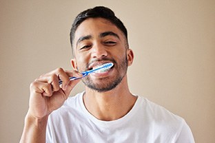 Man smiling while brushing his teeth