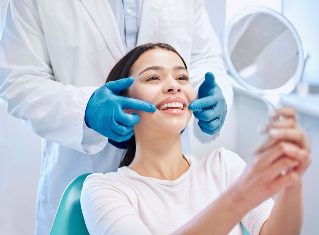 A woman in a dental chair looking at her smile in the mirror.