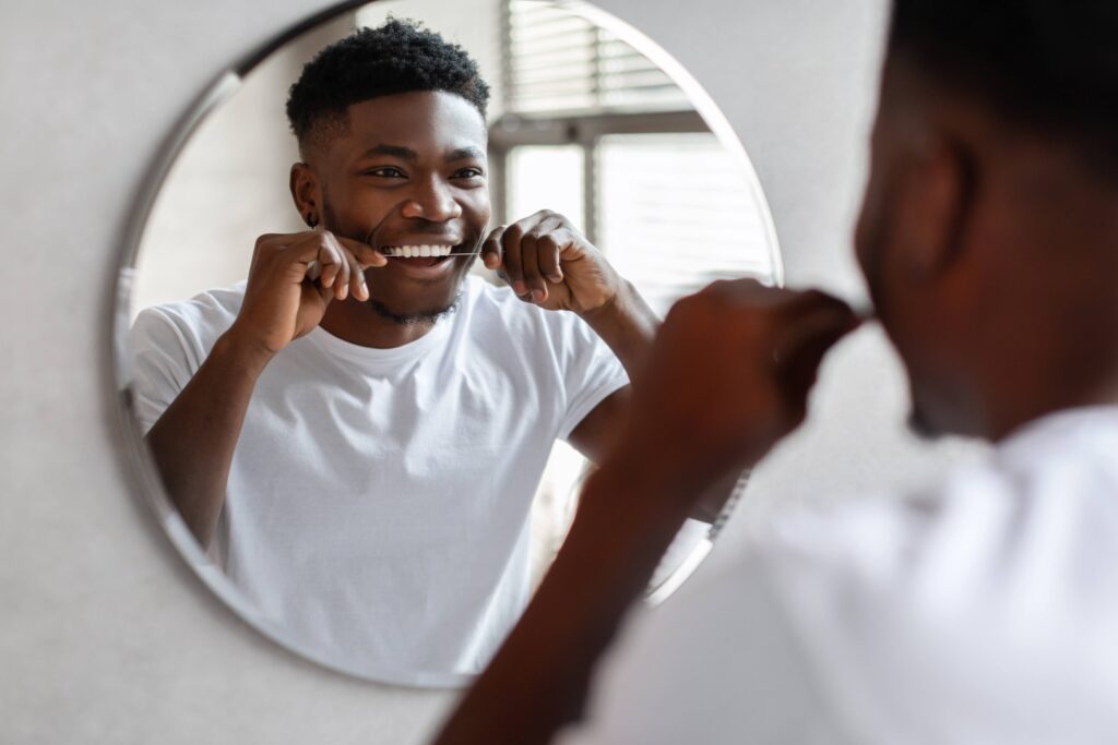 Man smiling while flossing in mirror